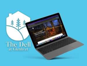 A laptop displaying a website for The Dell at Glenlivet, featuring a cozy cabin in a wooded setting, is shown against a blue background alongside The Dell logo. This website exemplifies innovative web design trends that are becoming popular among Inverness businesses.