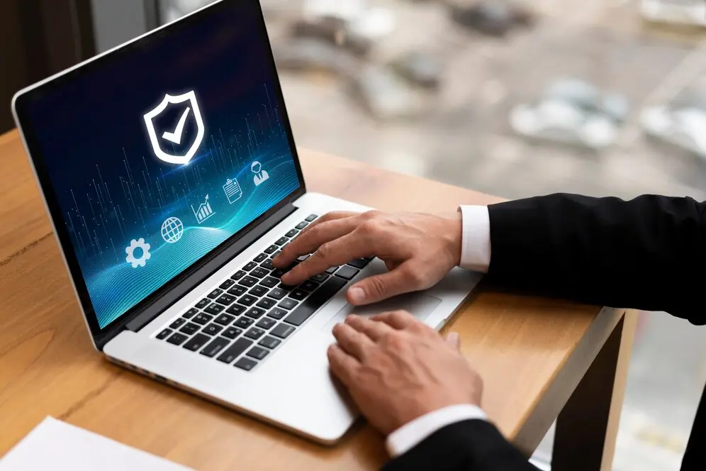 A person wearing a black suit uses a laptop displaying a cyber security interface with icons for security, global network, and analytics. The scene is set on a wooden desk with a blurred background, highlighting the importance of user-centric design in crafting websites that prioritize online safety.